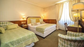 Ein Hotelzimmer mit zwei Betten, einem Schreibtisch, einem Stuhl und einer Lampe.