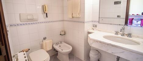 A bathroom with a toilet, bidet, sink, and mirror.