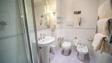 Une salle de bain équipée d’un lavabo, de toilettes, d’un bidet et d’une douche à parois en verre.