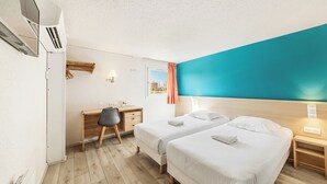Habitación de hotel con dos camas, un escritorio y un equipo de aire acondicionado.