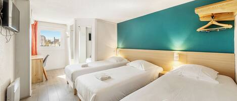 A hotel room with two beds, a desk, and a view of the city.