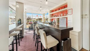 Una zona de bar con mostrador, taburetes y estanterías llenas de botellas.