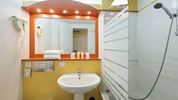 A bathroom with a sink, mirror, towel rack, and shower.