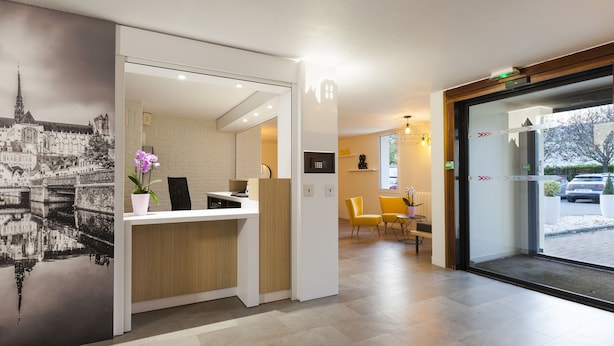 Een modern ontworpen receptiegedeelte, met een receptiebalie, een zithoek en een groot raam met uitzicht op buiten.