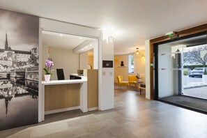 Een modern ontworpen receptiegedeelte, met een receptiebalie, een zithoek en een groot raam met uitzicht op buiten.