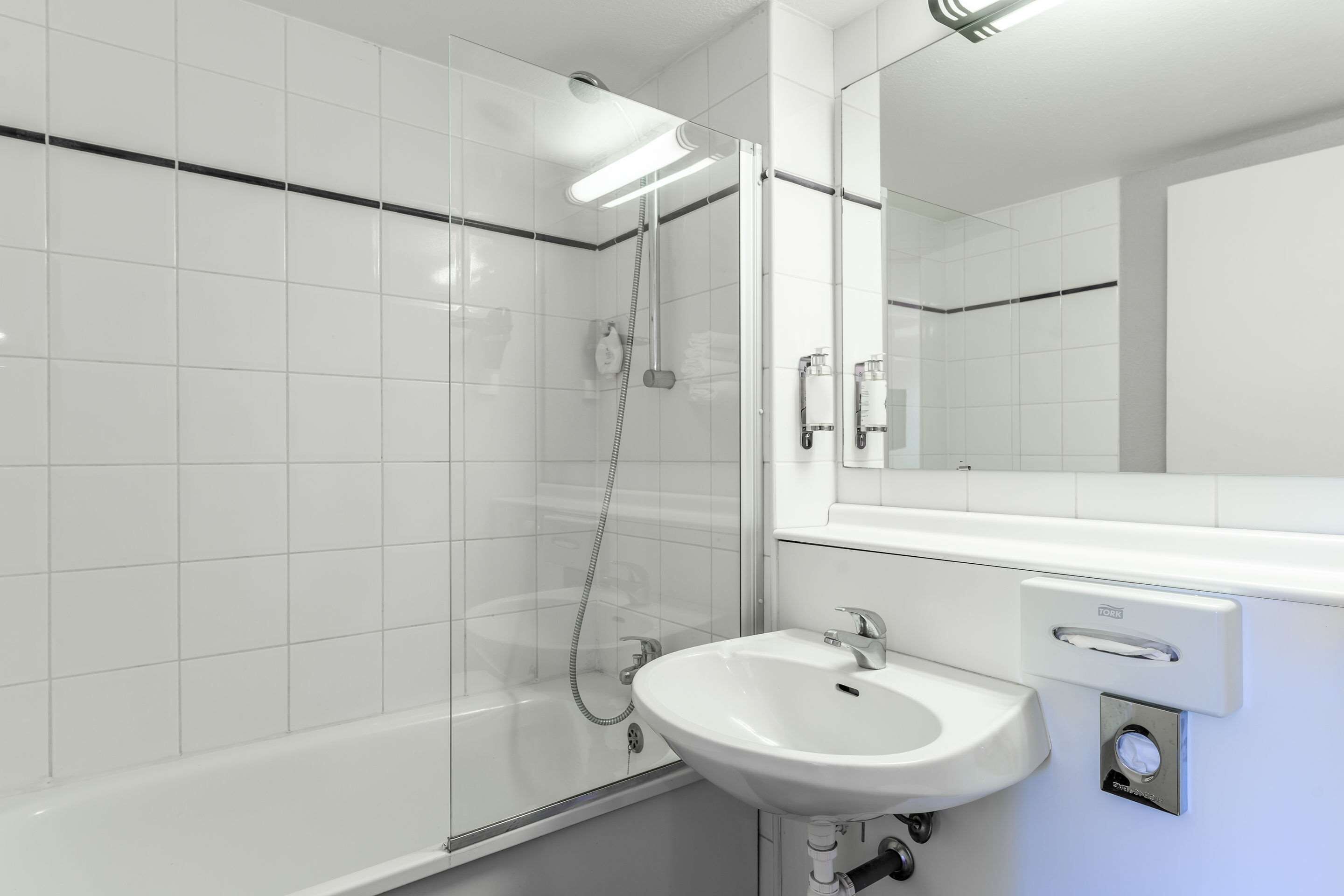 A modern bathroom with a glass-enclosed shower, a white sink, and a large mirror.