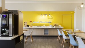 Een moderne keuken met een geel accentmuur, een ingebouwde koffiemachine en een ontbijtbalk met zitplaatsen.