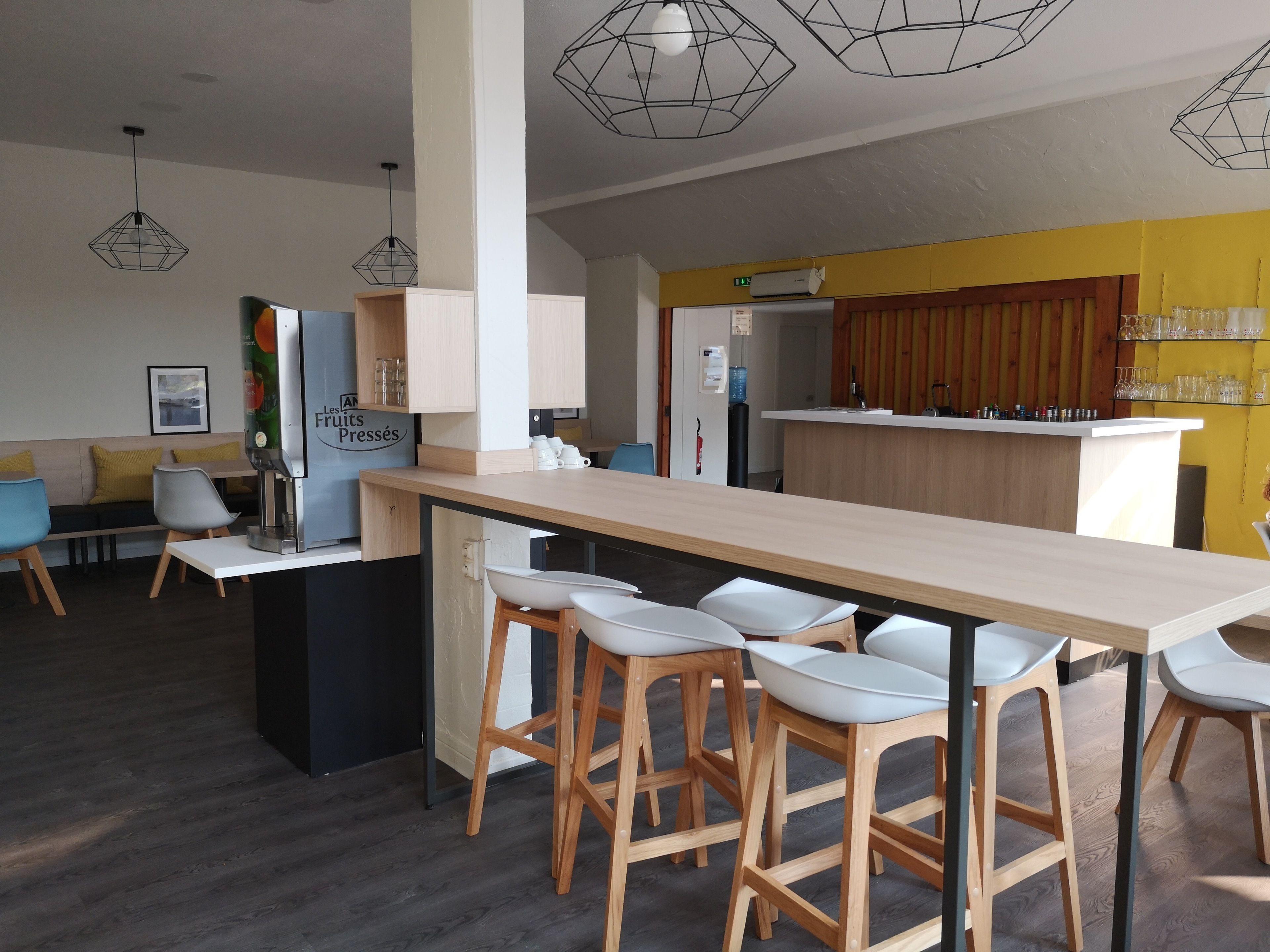 A modern kitchen with a central island, bar stools, and a seating area with a sofa and chairs.