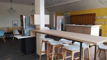 A modern kitchen with a central island, bar stools, and a seating area with a sofa and chairs.