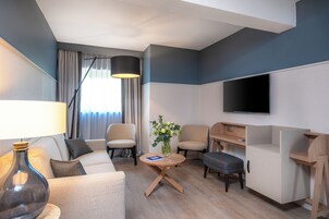 Una sala de estar moderna con sofá, sillones, una mesa de centro, televisor y escritorio.
