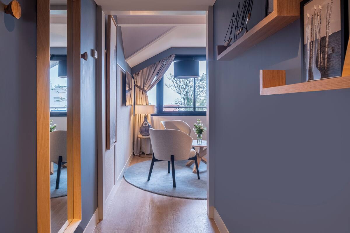 A modern hallway with wooden flooring, a round rug, and a dining area with a table and chairs.