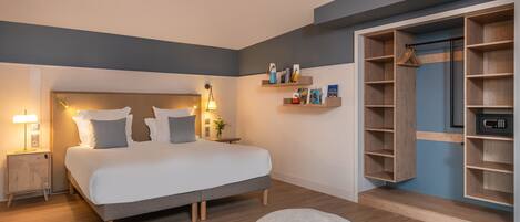 A modern bedroom with a bed, bedside tables, a nightstand, a round ottoman, a wall-mounted shelf with books, and a wardrobe.