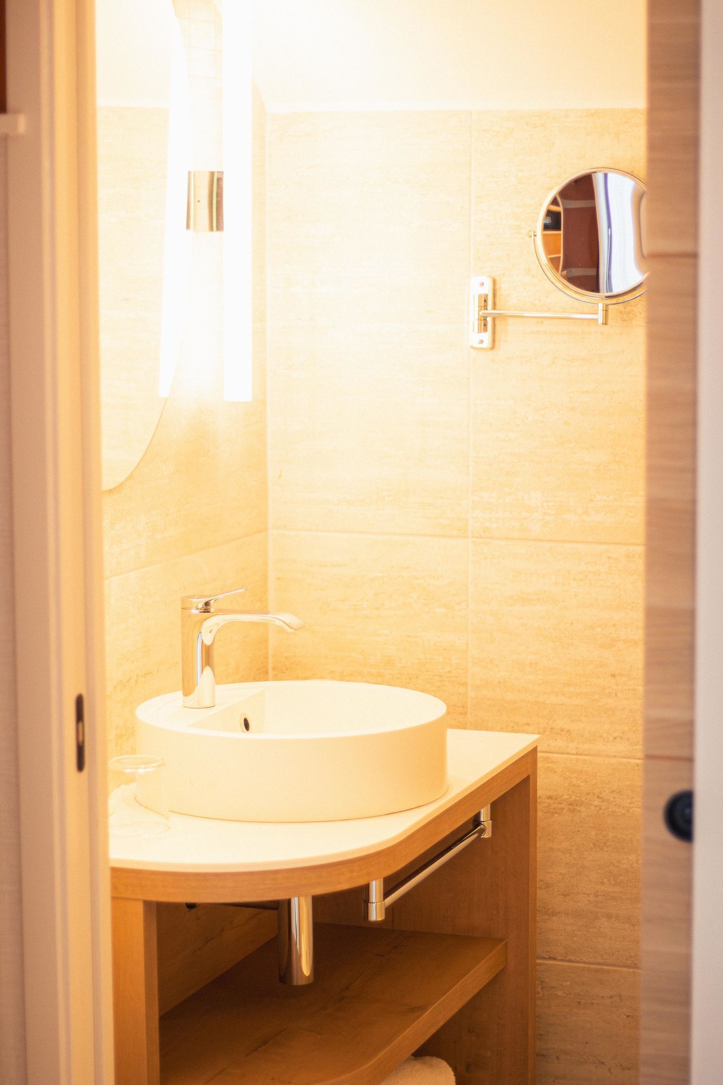 A bathroom with a round sink, a mirror, and a towel rack.