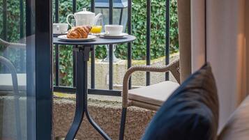 Un balcón con una mesa dispuesta para el desayuno, que incluye croissants, zumo de naranja y café.