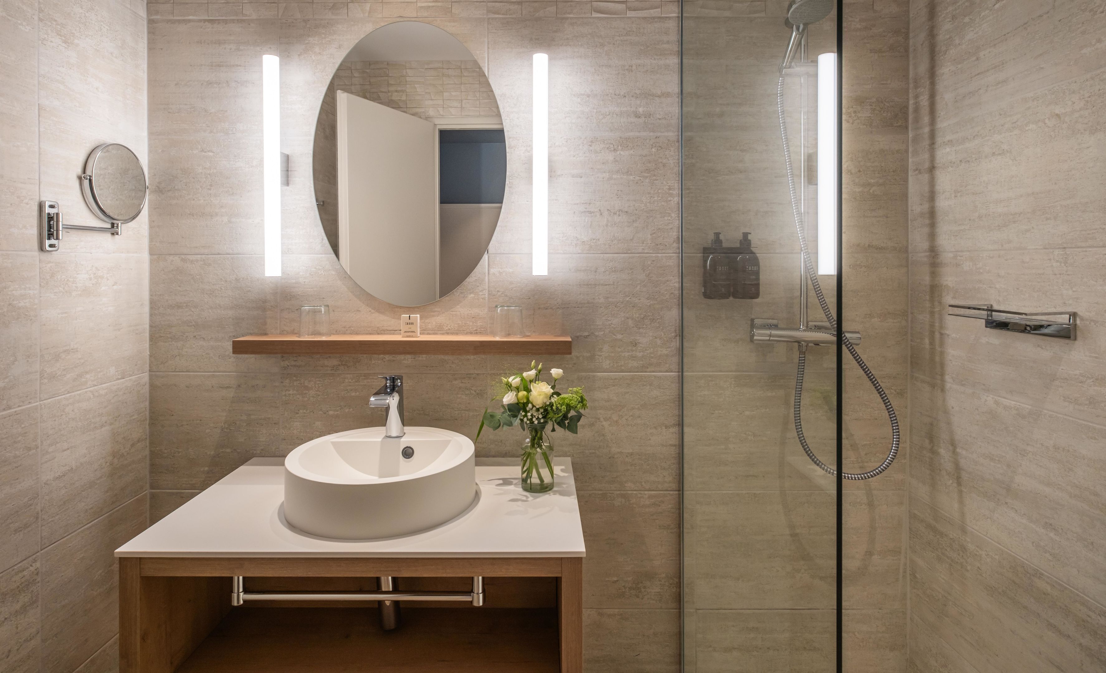 A modern bathroom with a round sink, a mirror, and a shower.