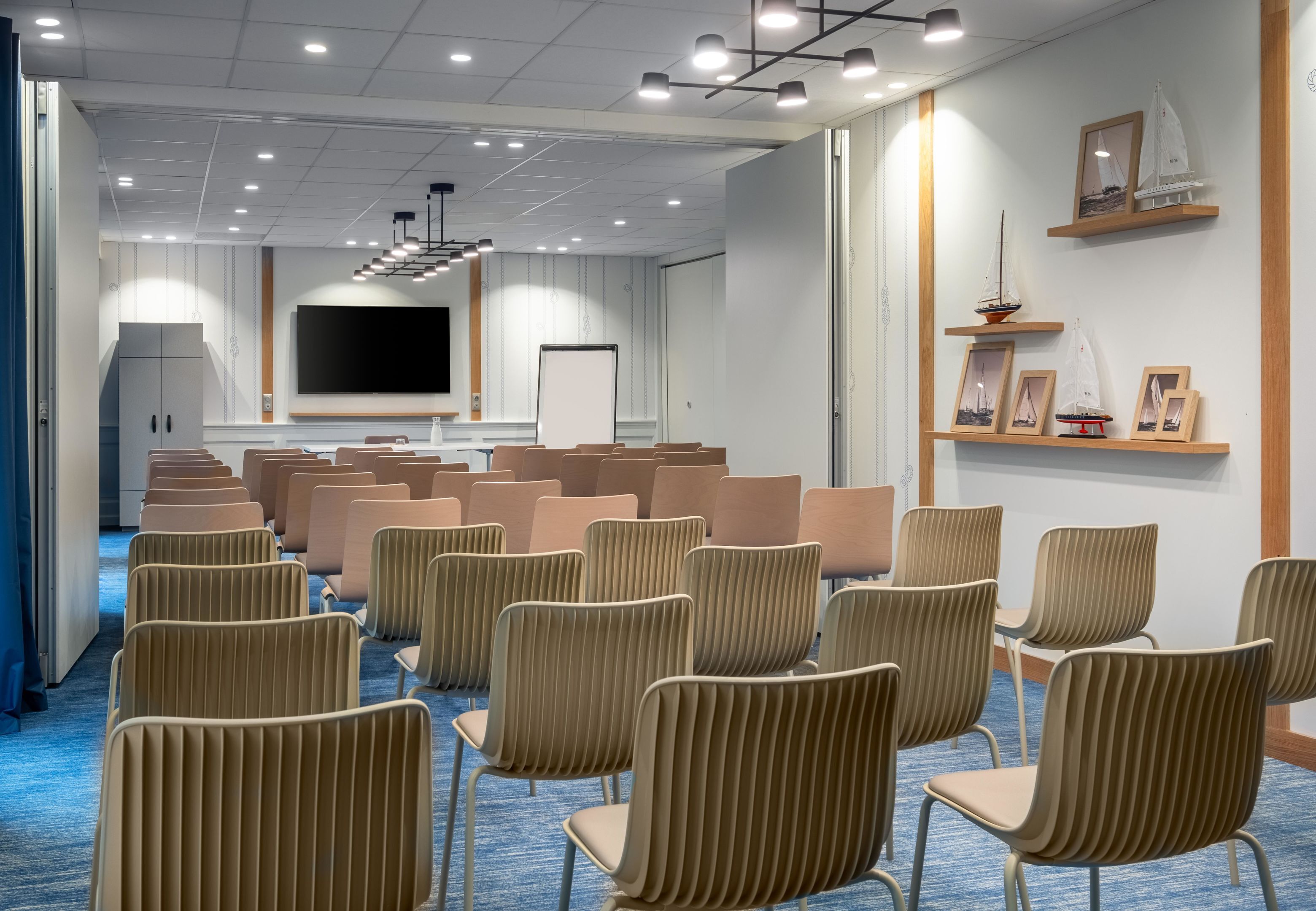 A conference room with rows of chairs, a large screen, and a whiteboard.