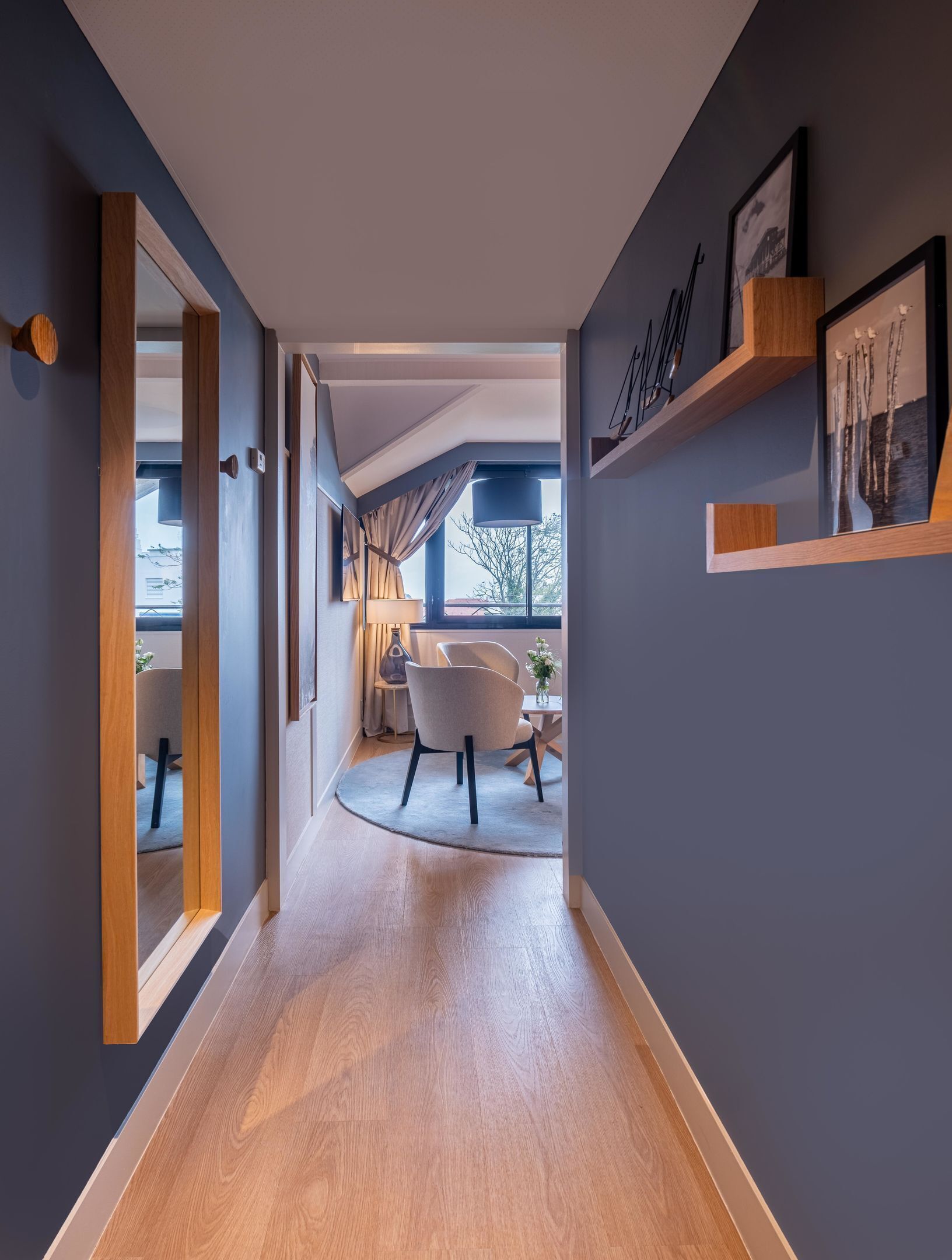 Un couloir moderne avec un plancher en bois, un banc incurvé et une vue sur l’espace salle à manger.