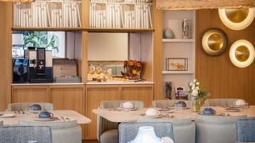 Un restaurant doté de plusieurs tables, d’un appareil à café et d’une bibliothèque remplie de livres.