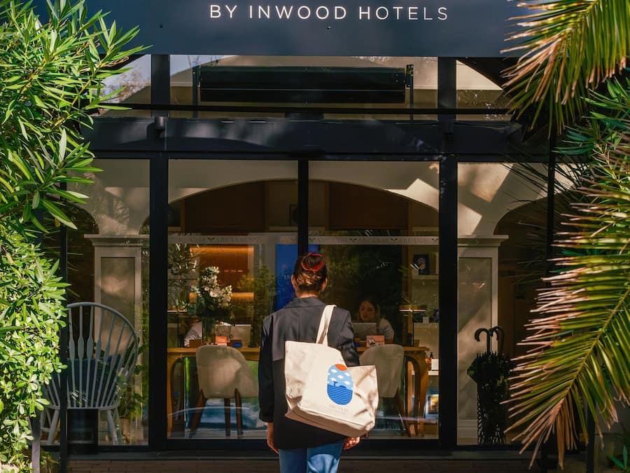 Eine Person geht auf den Eingang eines Hotels namens 'ARCÂNSE BY INWOOD HOTELS' zu.