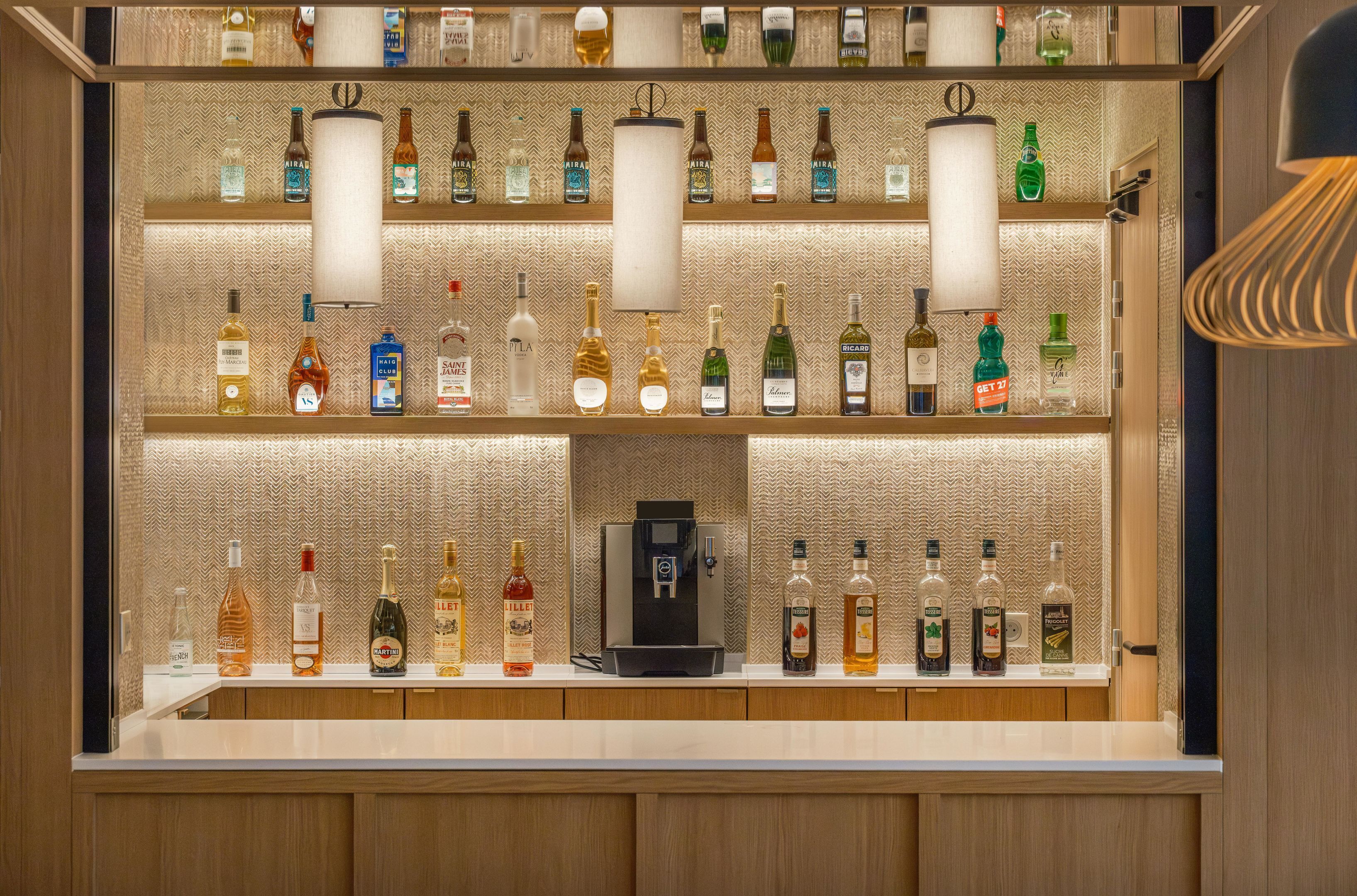 A bar area with multiple shelves of liquor bottles and a coffee machine.