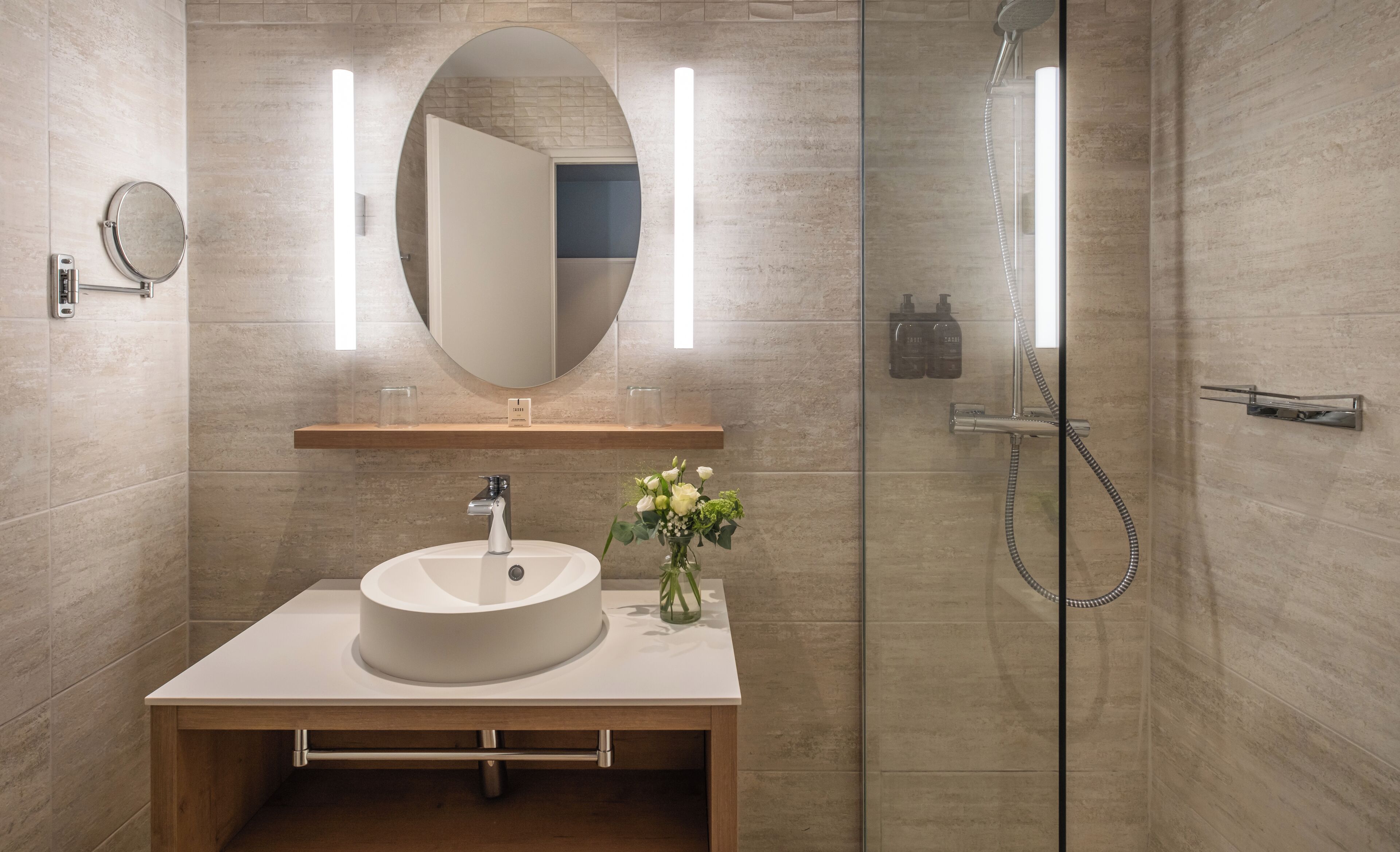 A modern bathroom with a round sink, a mirror, and a shower.