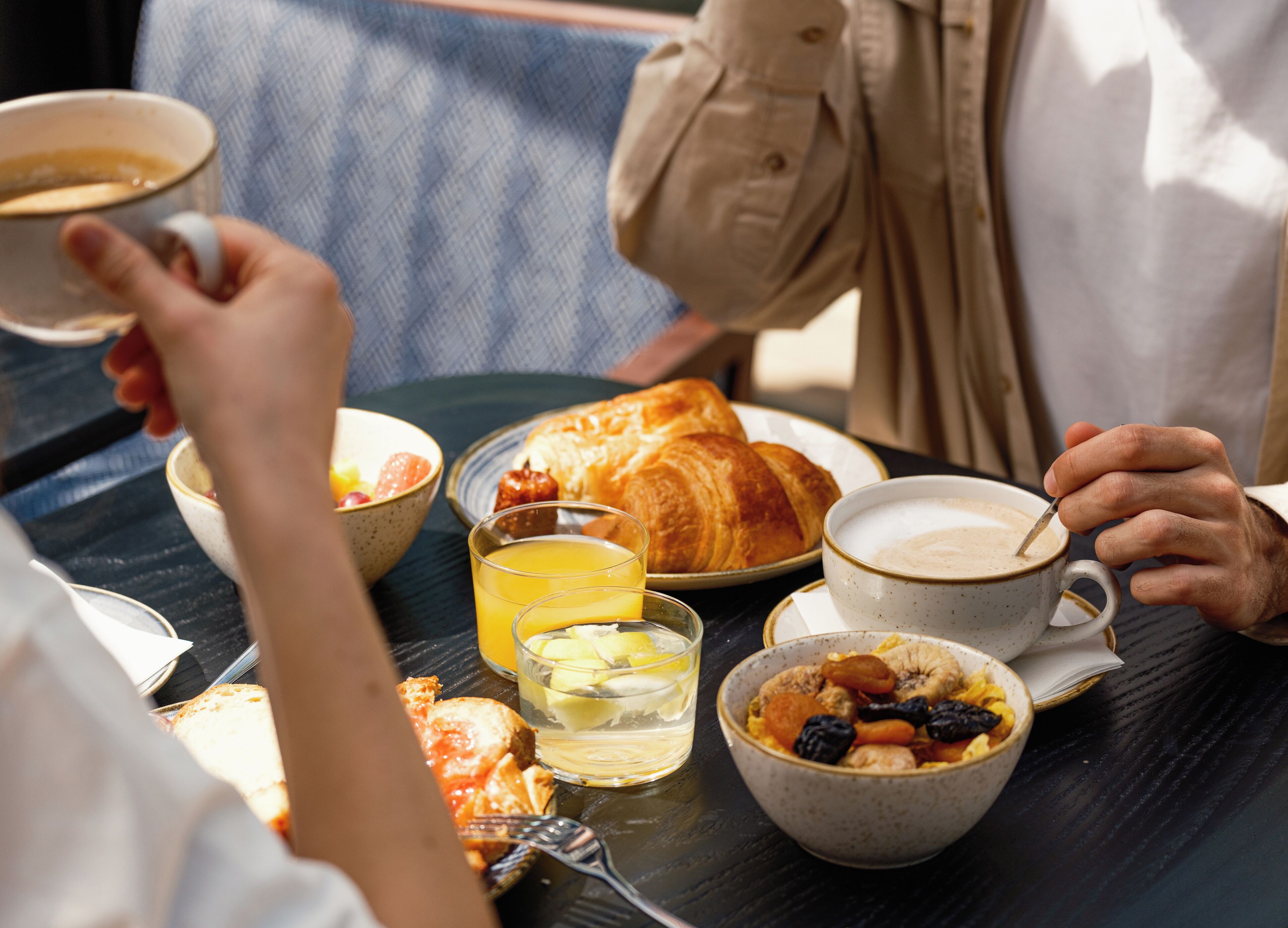 Colazione con croissant, caffè e frutta su un tavolo.
