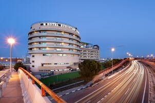 Un hotel moderno con fachada curva, varios balcones y un cartel llamativo.