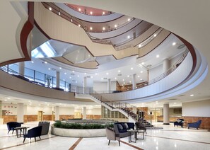 A spacious lobby with a central staircase, seating areas, and a reception desk. - Eurostars Madrid Foro (Tres Cantos)