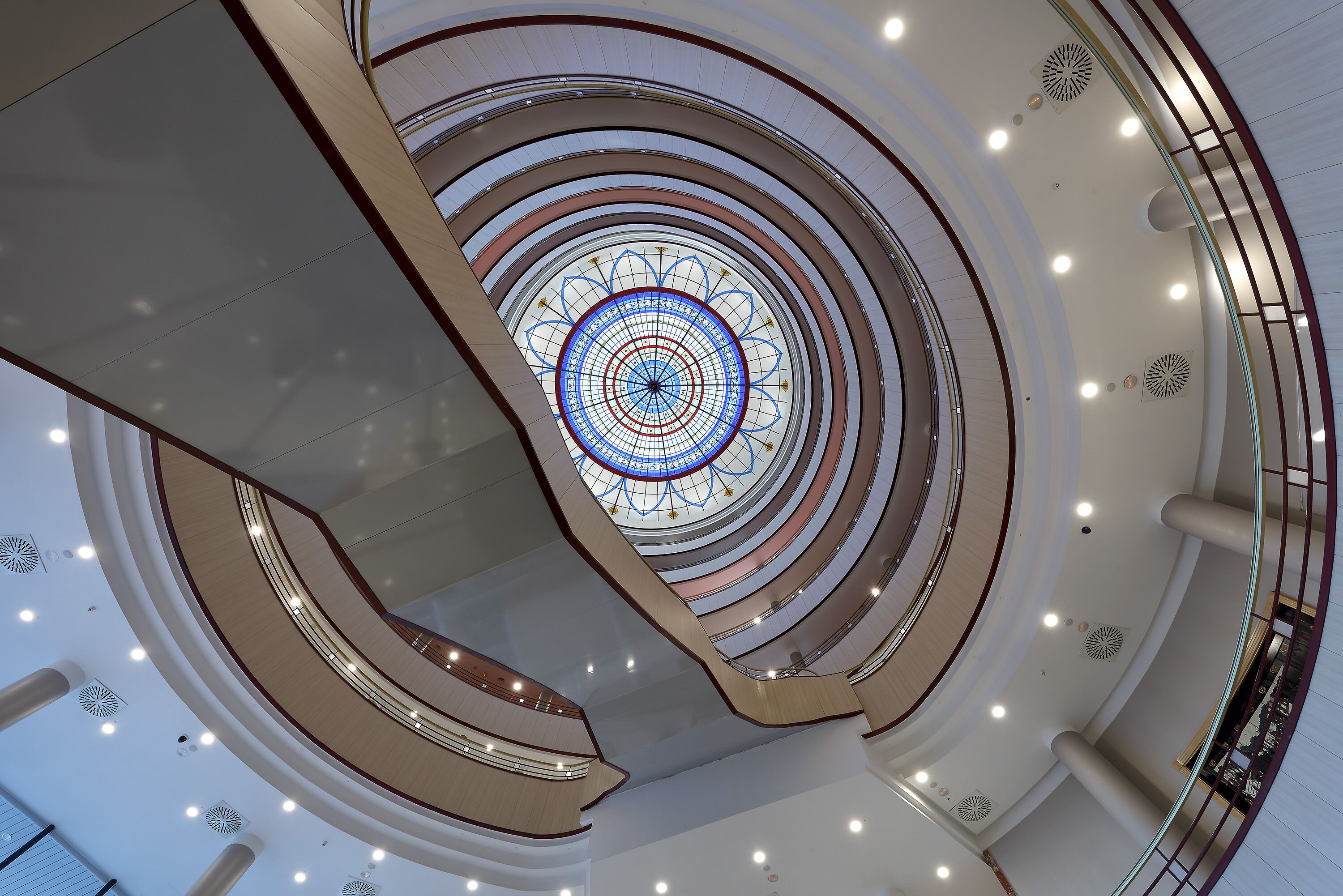 A multi-level atrium with a central glass dome and multiple floors connected by curved walkways.