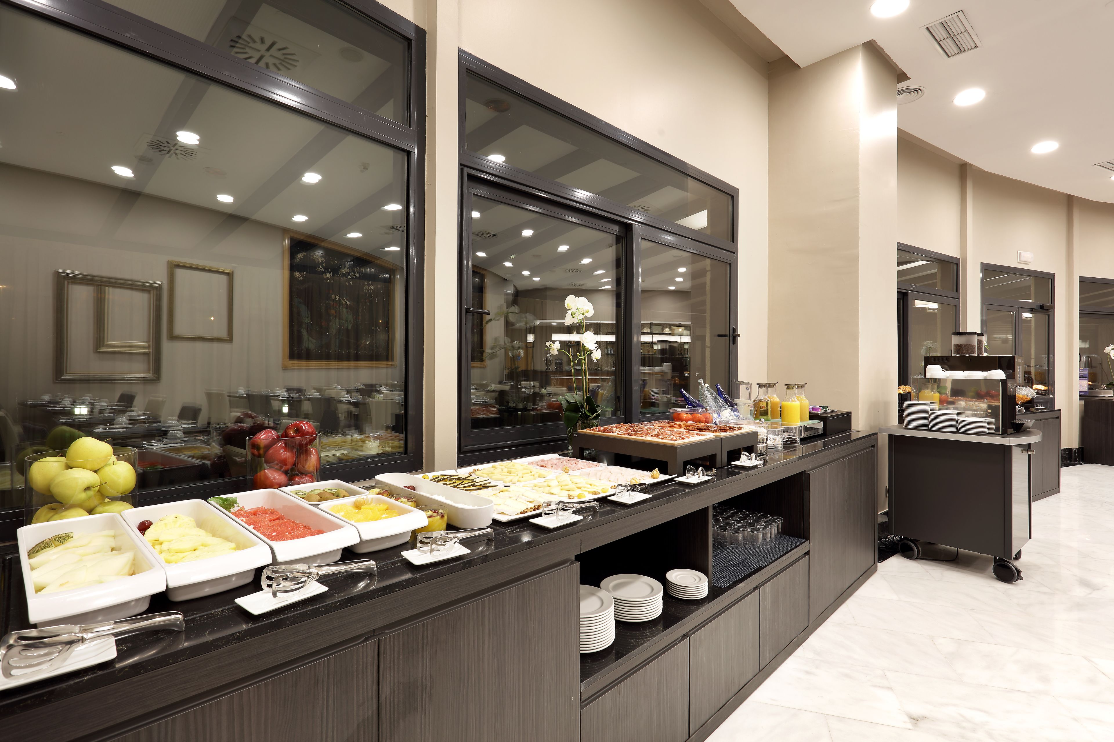 A buffet with various food options, a fruit display, and a beverage station.