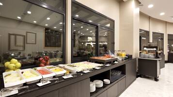 A buffet with various food options, a fruit display, and a beverage station.