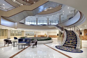 A spacious lobby with a central seating area, a circular water feature, and a grand staircase. - Eurostars Madrid Foro (Tres Cantos)