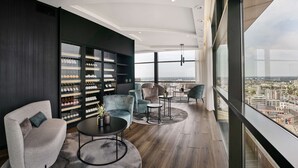 A modern lounge with a large window, a wine rack, and comfortable seating. - Radisson Blu Hotel, Hasselt (Hasselt)