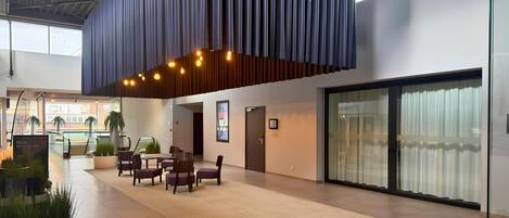 Un espacio interior amplio con zona de estar, un ventanal grande y un diseño de techo moderno.