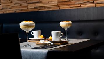 A table with two dessert glasses, two white cups, a spoon, and a small plate with a pastry.