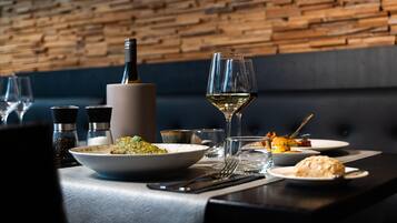 Una mesa de comedor con una botella de vino, copas y platos de comida.
