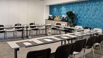 A conference room with a long table, chairs, water bottles, and a blue textured wall.