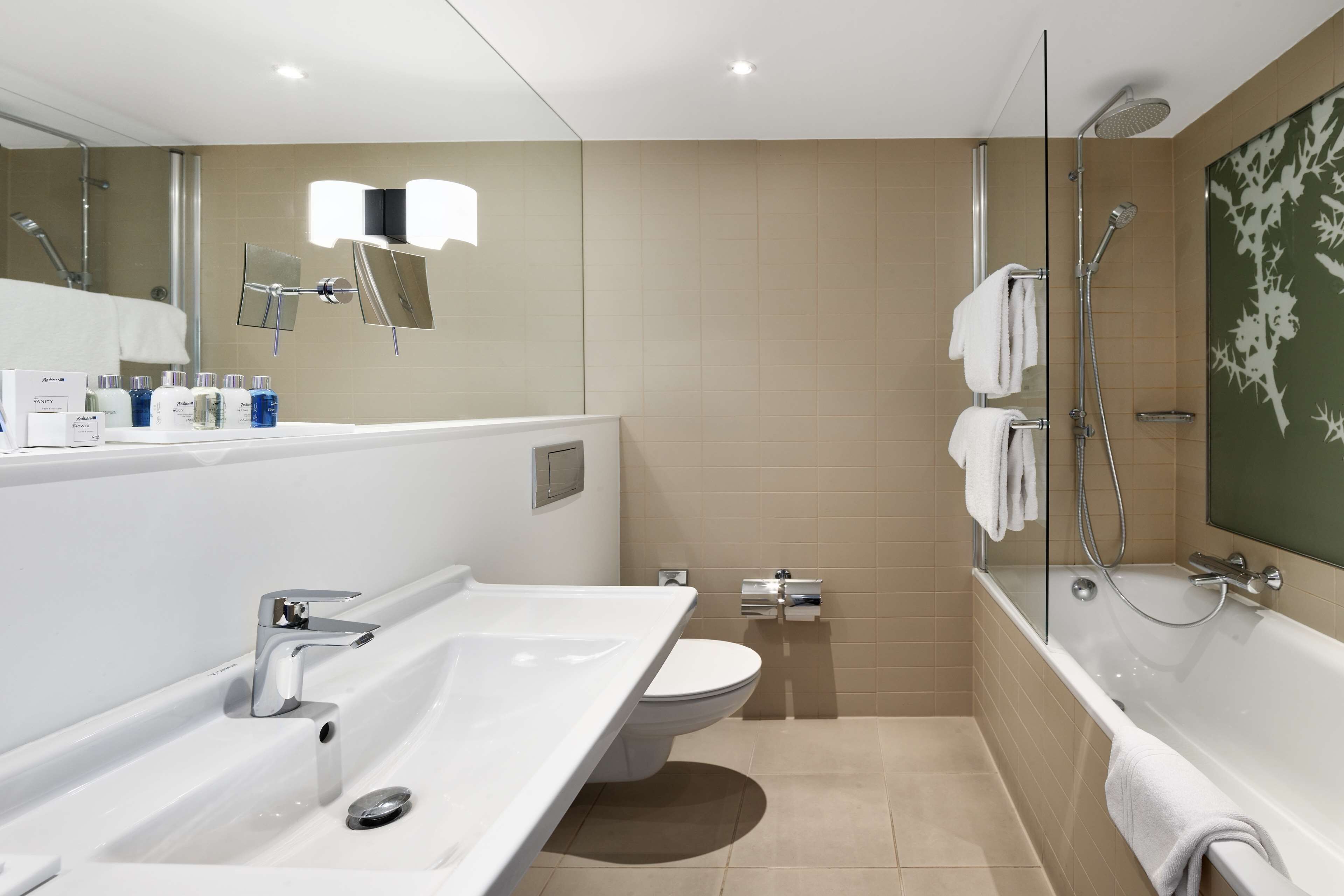 A modern bathroom with a large sink, toilet, and bathtub.