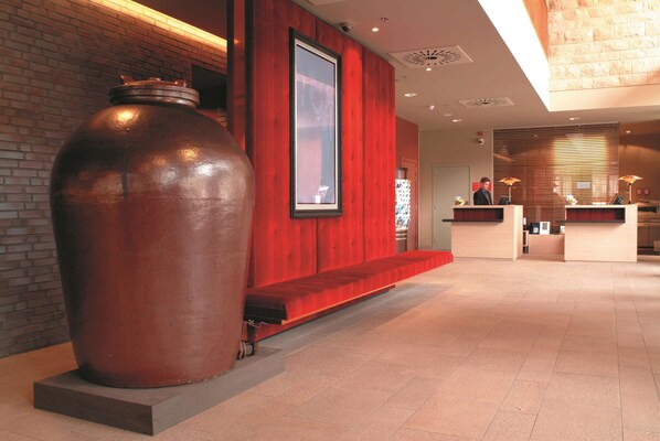 A reception area with a large metal sculpture, a red wall, and a reception desk. - Radisson Blu Hotel, Hasselt (Hasselt)