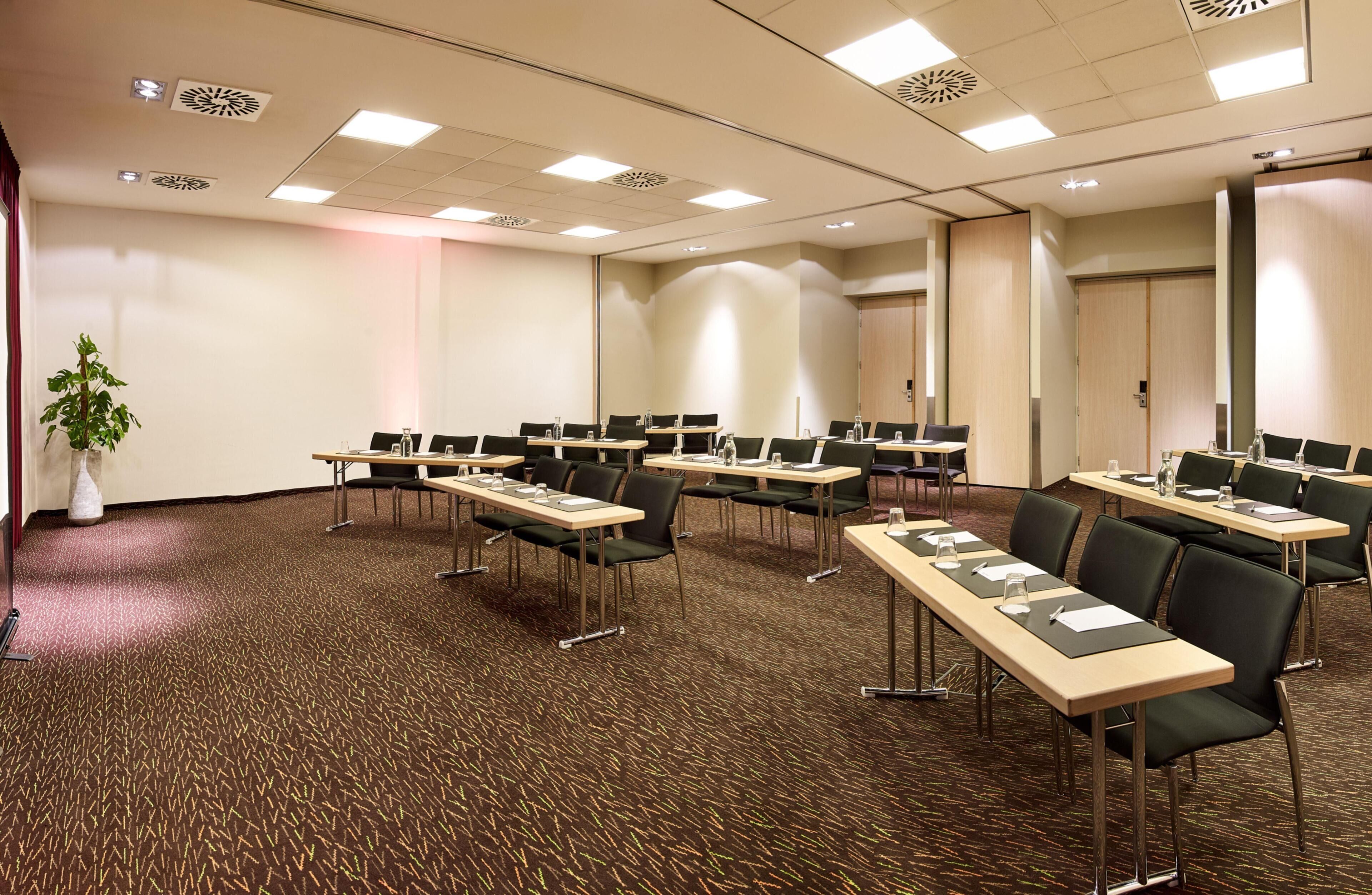 A conference room with multiple tables, chairs, and a potted plant.