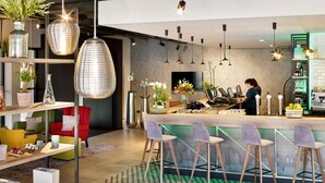 A modern bar area with a bar counter, seating, and a television screen. - Radisson Blu Hotel, Hasselt (Hasselt)