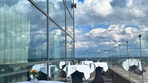 A rooftop restaurant with tables set for dining, large windows, and a view of the cityscape. - Radisson Blu Hotel, Hasselt (Hasselt)