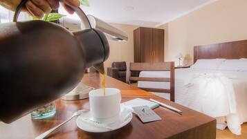 Una mano sirve café en una taza sobre la mesa de una habitación de hotel.