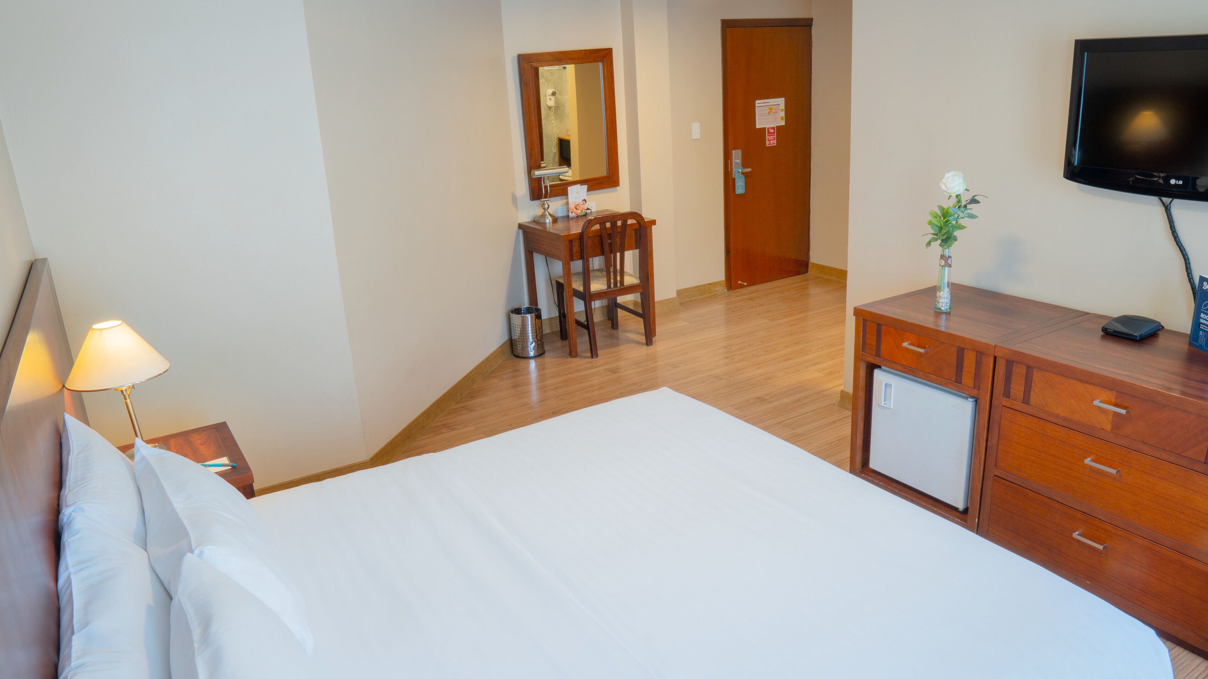 Une chambre d’hôtel comprenant un lit, un bureau avec une chaise, une télévision et une commode.