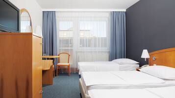 Hotelkamer met twee bedden, een bureau, een stoel, een televisie en een raam met gordijnen.
