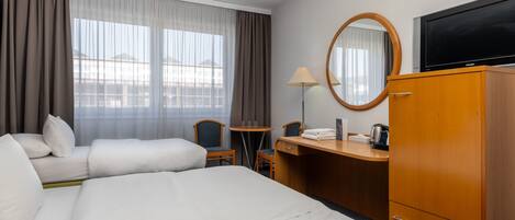 Une chambre d’hôtel comprenant un lit, un bureau, une chaise, une télévision et une armoire.