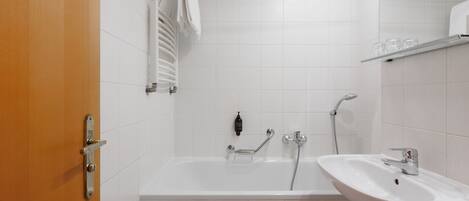 Un baño con bañera, lavabo y perchero para toallas.