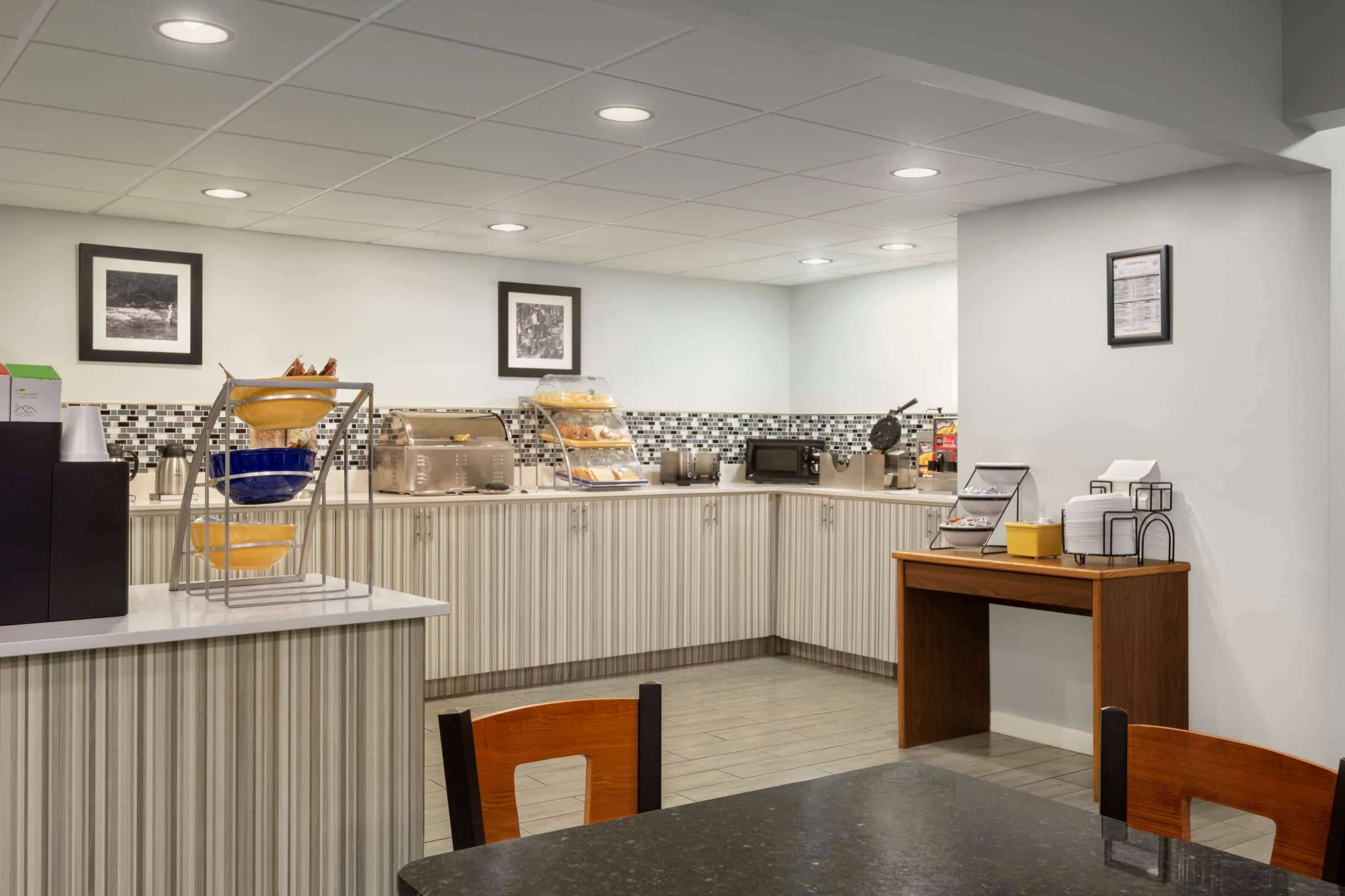 Un área de cocina moderna con mostrador, cafetera y vitrina con alimentos.