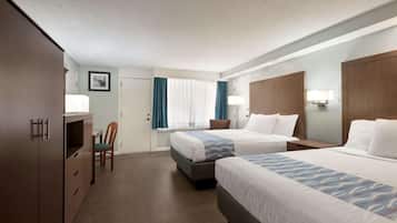 A hotel room with two beds, a desk, a chair, and a wardrobe.