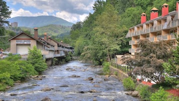 Une rivière bordée de rochers, entourée de verdure et de bâtiments, notamment un motel et un hôtel doté de balcons.